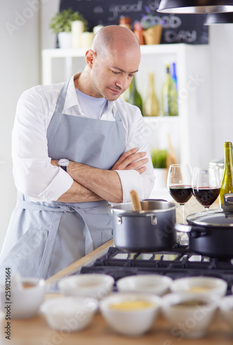 Handsome man is cooking on kitchen and smiling