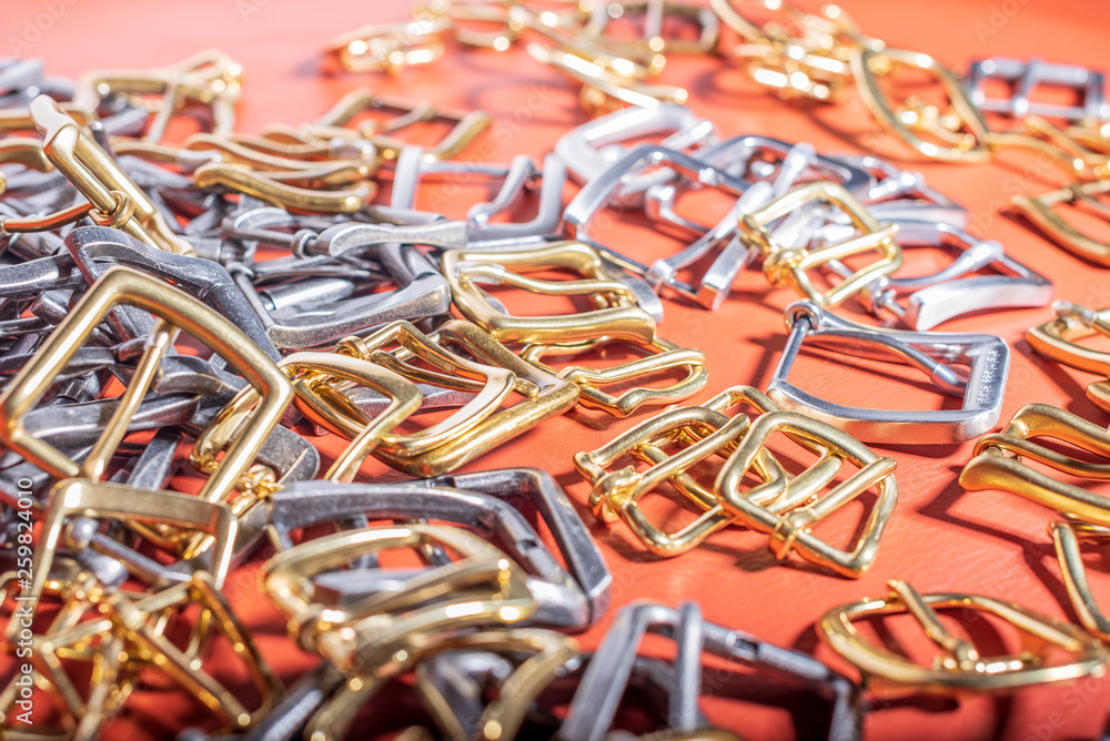A lot of metal buckles for belts on red genuine full grain leather. Leather workshop A lot of metal buckles for belts on red genuine full grain leather. Leather workshop