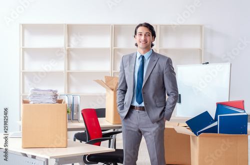 Young man employee with boxes in the office 