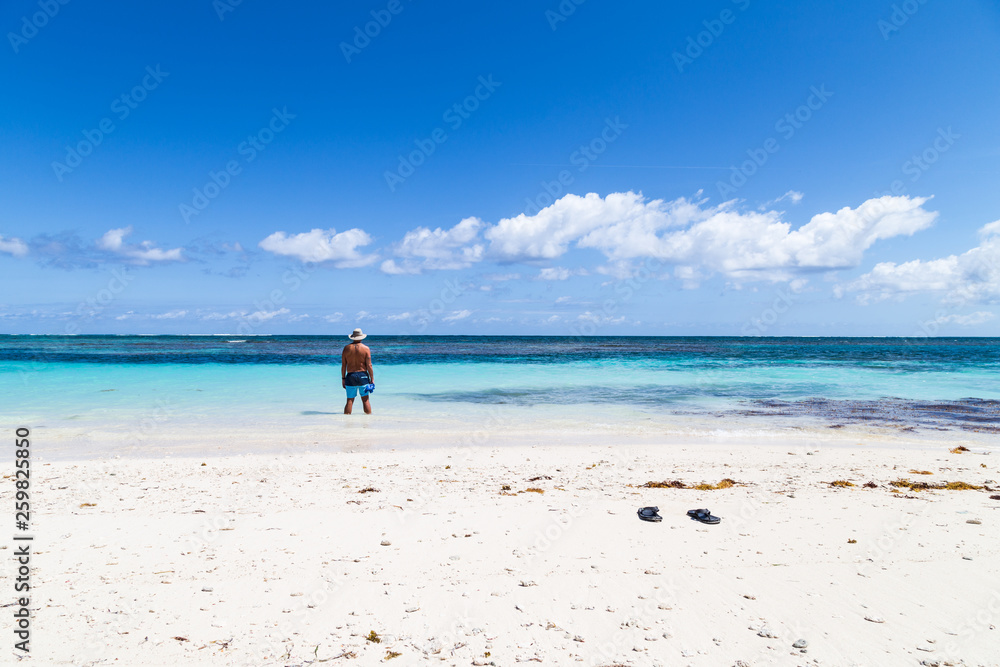 Man looking at blue sky a nd water at tropical beach.
