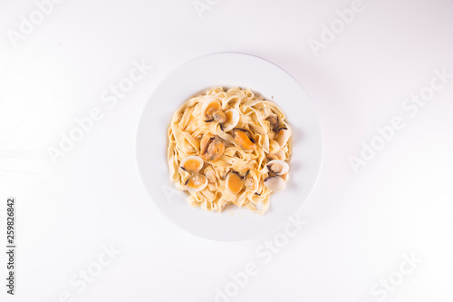 noodle dish with mussels and clams on white background © Imaxepress