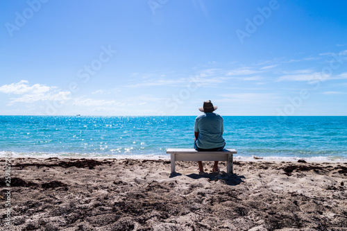 Man sitting on the bench at tropical beach. © Satoshi Kina