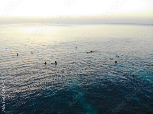 Aerial view of surfers on their board waiting the waves during sunset, big waves tropical blue ocean, drone view of surfer catching the blue waves, Bali, Indonesia