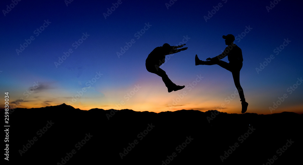 Silhouettes of two male fighters on sunset background.