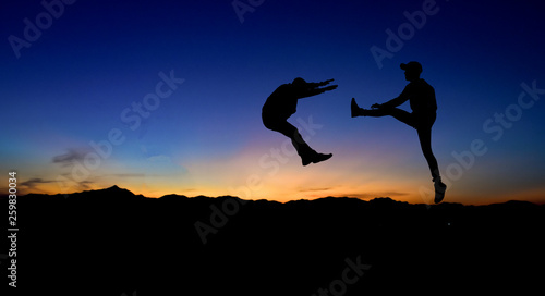 Silhouettes of two male fighters on sunset background.