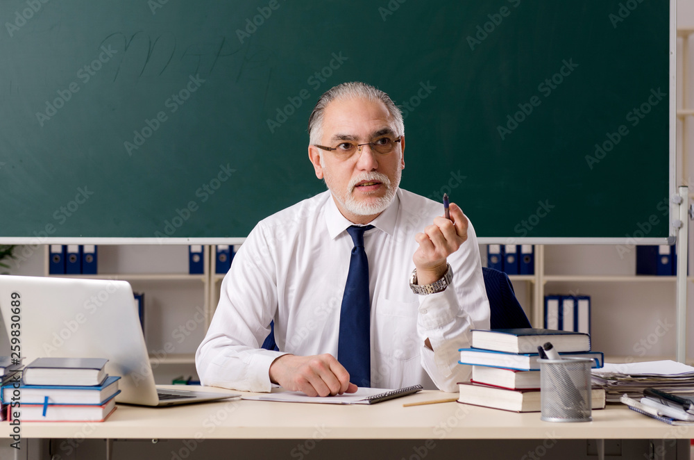 Aged male teacher in front of chalkboard Aged male teacher in front of chalkboard