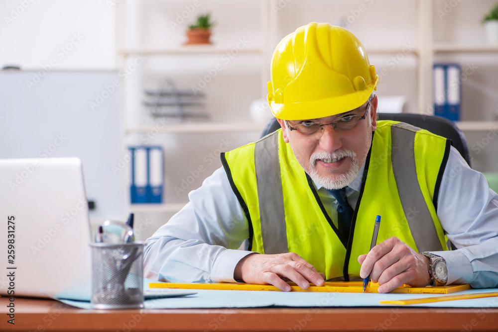 Aged construction engineer working in the office Aged construction engineer working in the office