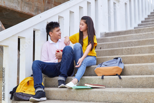 students friends sitting on stairs using book