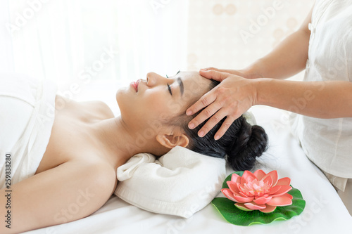 beautiful and healthy young woman relaxing with face massage at beauty spa salon
