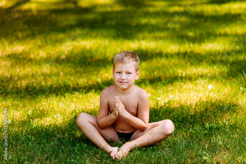 boy Yogi sits on green grass