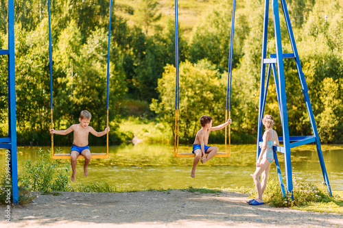 children sit on a swing on the Playground in the Park.