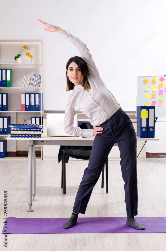 Young female employee doing exercises at workplace Young female employee doing exercises at workplace
