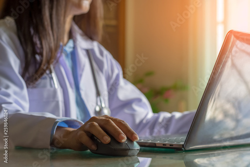 Female doctor or medical student hand using wireless mouse and work on laptop computer in medical room at clinic or hospital. photo