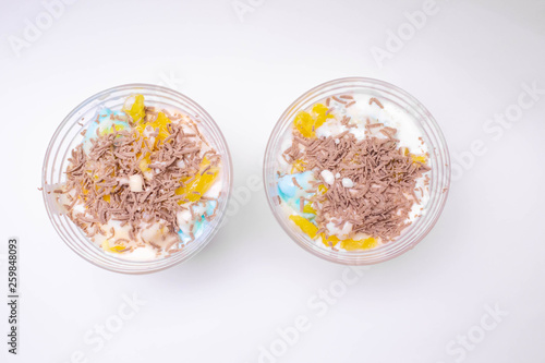 tasty homemade dessert in a sundae with colorful ice cream, fruit, chocolate chips on a white background for children and adults.