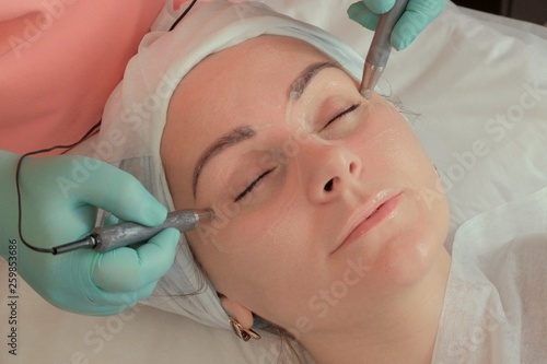 Close-up of a woman taking a procedure in a beauty salon. Microcurrent stimulation of the skin around the eyes. Moisturizer removes dark circles under the eyes