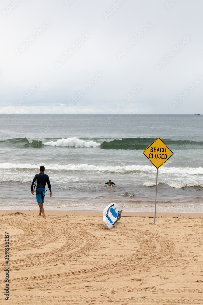Obraz premium Surfeur sur la plage de Manly à Sydney à côté d'un panneau interdisant la baignade