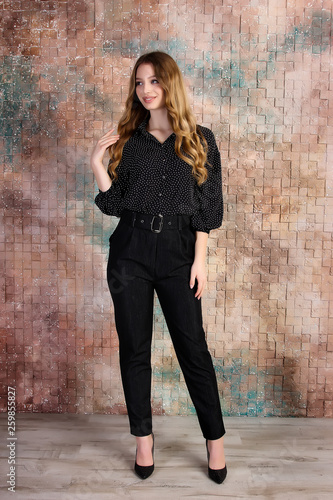 Business woman in pants and shirt on brick wall background. Office and business style. Studio photo.  © Oleksii