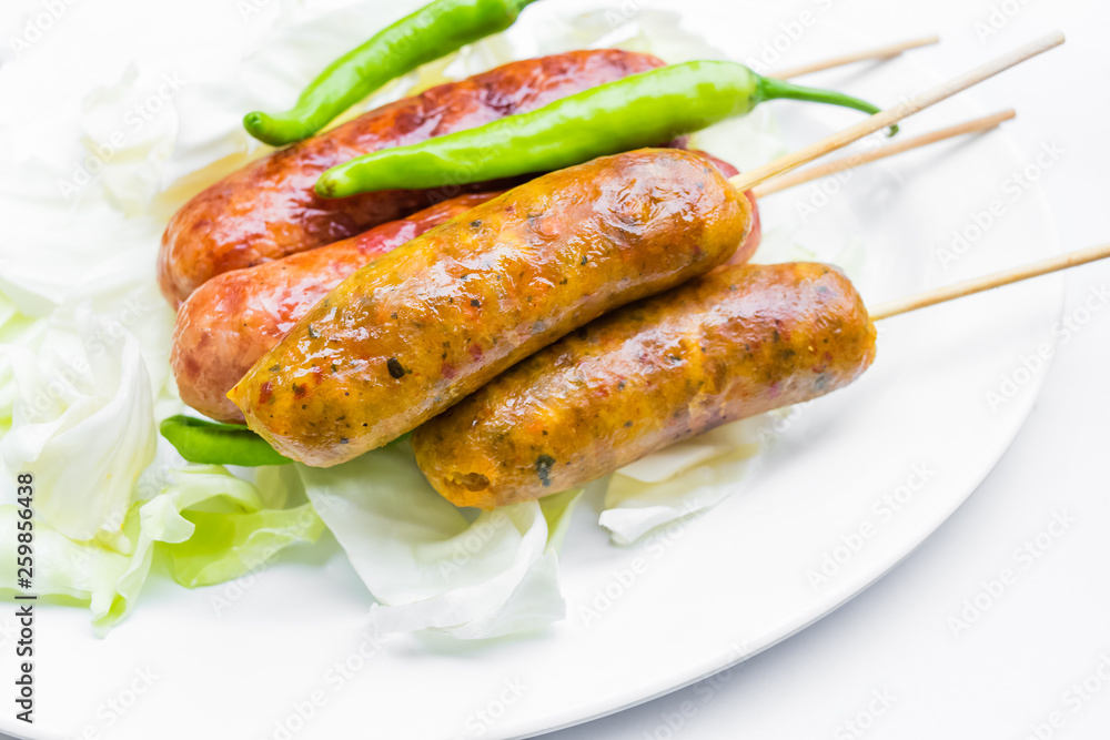 Pork sausage in a white dish with green peppers.