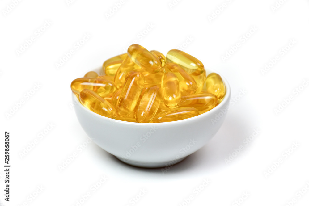 Close up of gold fish oil capsules in cup isolated on white background. Omega 3 with Vitamin E. Salmon fish capsules. Supplementary food background view. Close up of gold fish oil capsules in cup isolated on white background. Omega 3 with Vitamin E. Salmon fish capsules. Supplementary food background view.