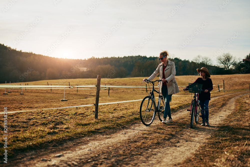 Fototapeta premium Mother and daughter with bicycles on countryside.