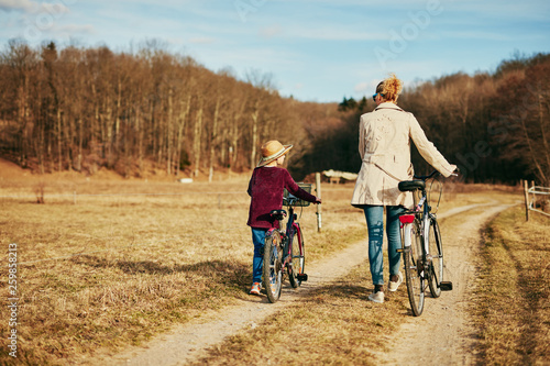 Mother and daughter with bicycles on countryside.