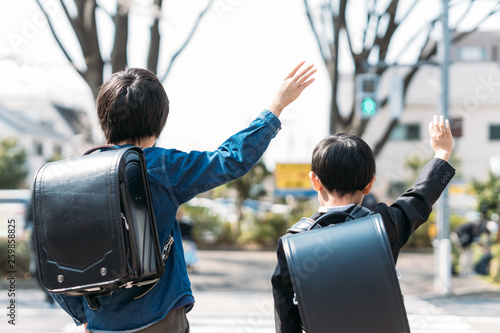 交差点で手を挙げる小学校高学年生と1年生 photo