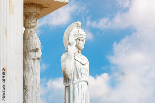 Woman with spear statue. Replica on ancient greek Athena sculpture in a public park. Cracked face of female Greek sculpture.