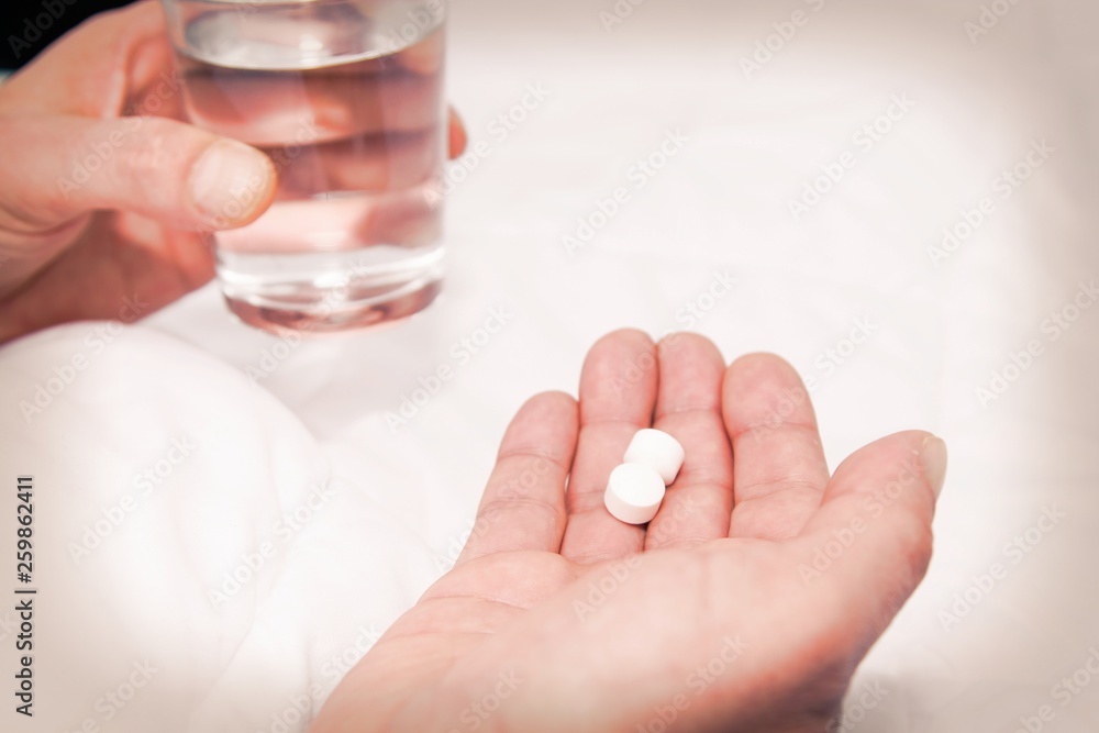 sick man in bed holding a glass of water and pill sick man in bed holding a glass of water and pill