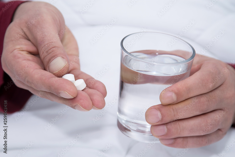 man holding a glass of water and pill man holding a glass of water and pill