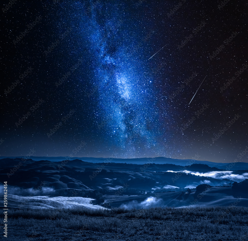 Milky way with falling stars and foggy valley in Italy