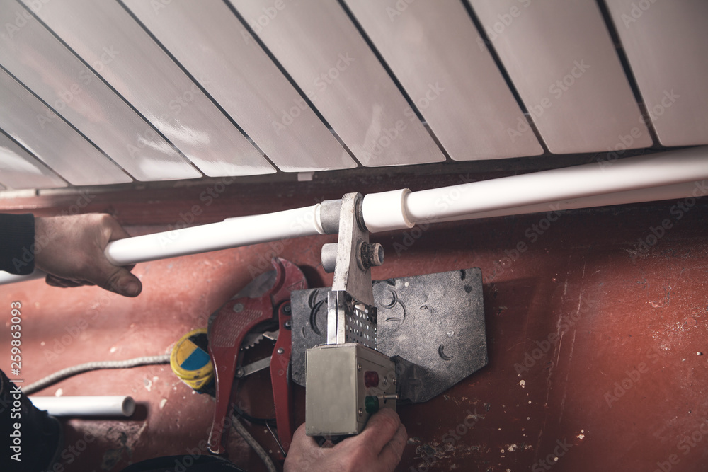 Worker connecting plastic pipe. Installing water heating radiator Stock