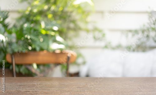 Wooden table in blur background that contains chair in behind
