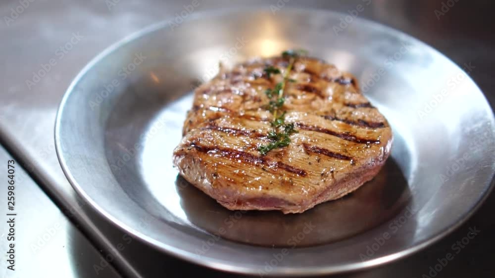 Close up slow motion view on hot steam coming up from black grill frying pan with delicious grilled beef meat Close up slow motion view on hot steam coming up from black grill frying pan with delicious grilled beef meat