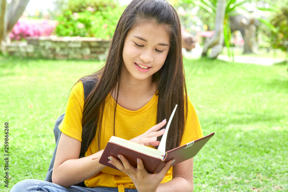 Fototapeta premium Female teenager reading book in park