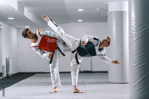 Two Caucasian sporty men sparring in tekwondo fittings barefoot. photo