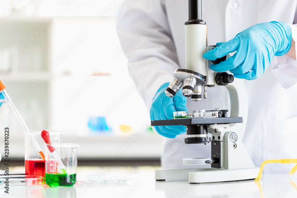 Scientist adjusting microscope for experiment.. Scientist adjusting microscope for experiment..