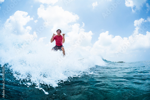 Happy surfer rides the wave and shows the Shaka sign