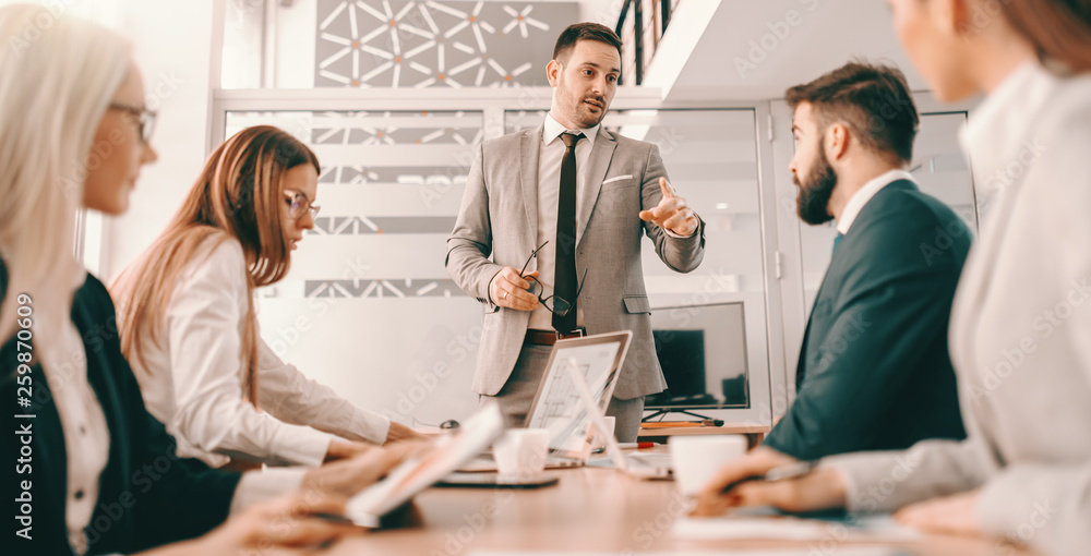 Obraz premium Handsome CEO in formal wear having meeting with his employees in boardroom. Create the kind of climate in your organization where personal growth is expected, recognized and rewarded.