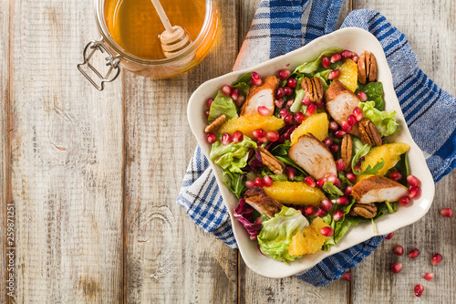 Spring salad with chicken, pomegranate, orange, pecan nuts and honey.