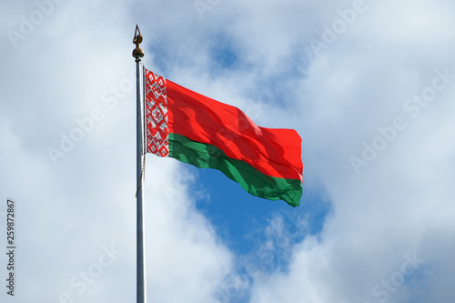 The national flag of the Republic of Belarus develops against the sky