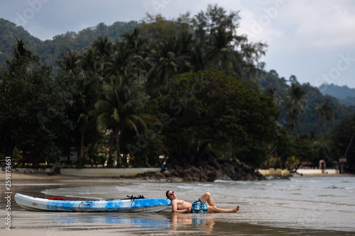 Happy young man lying near a kayak boat on Ko Chang  Thailand in April  2018 - Best travel destination for happiness