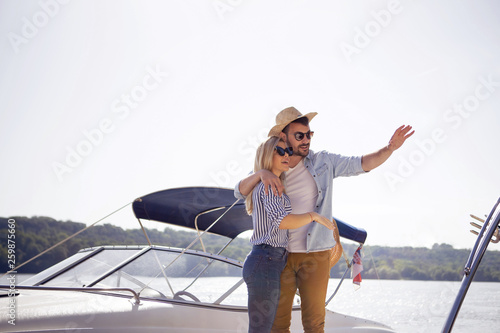 A Handsome young man shows his beautiful girlfriend where they'll be driving a new speedboat. © borevina
