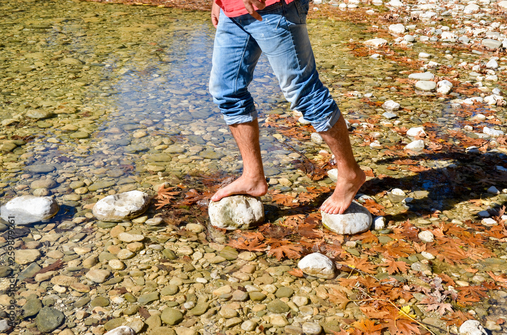 passing the river on the stonen young man feet river voidomatis zagoria ioannina  greece