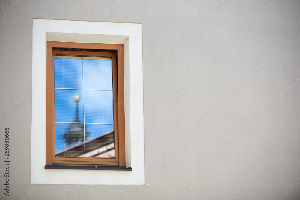 Fototapeta premium Ein Kirchturm in Tirol spiegelt sich im Fenster einer Hauswand