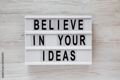 'Believe in your ideas' words on modern board over white wooden background, top view. Flat lay, from above, overhead. © Liudmyla