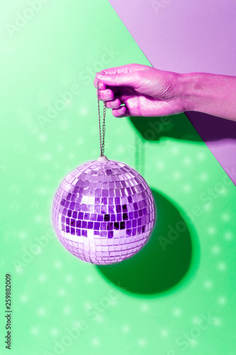 Shiny disco ball on a bright pastel creative background. Pop disco music style attributes eighties