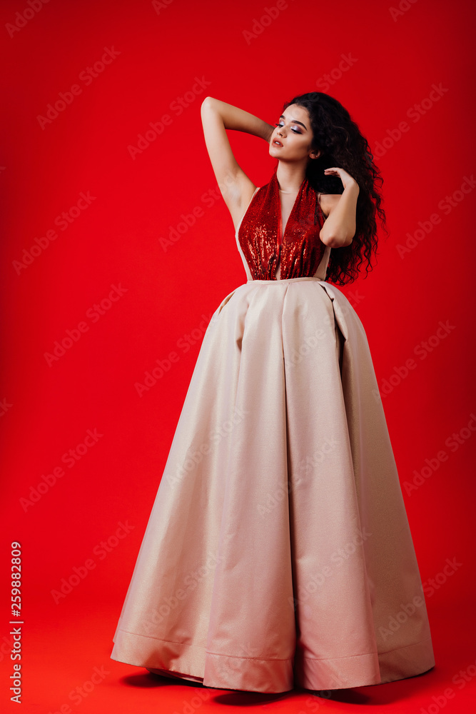 Amazing model in the red evening dress,standing in the studio, looking away, indoor shooting, model, beautiful face, glamour, makeup, waving hair , brunette, perfect body, beauty, fancy, sexy 