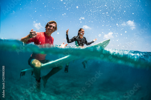 Young couple of surfers having fun in the tropical ocean
