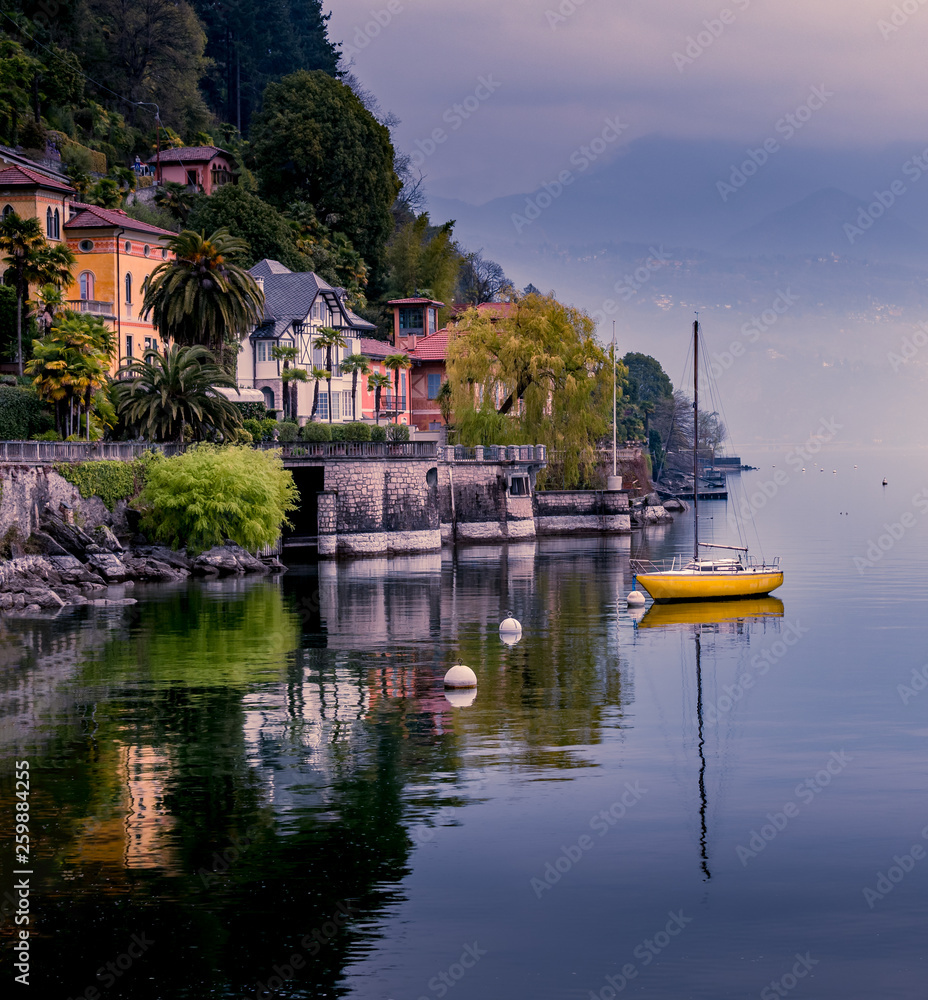 Image of cannero riviera at the lake maggiore with yellow sailing boat and buildings at the front of the lake