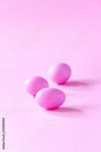 Three small pink candy eggs on pink background. Easter celebrate concept. Copy space.